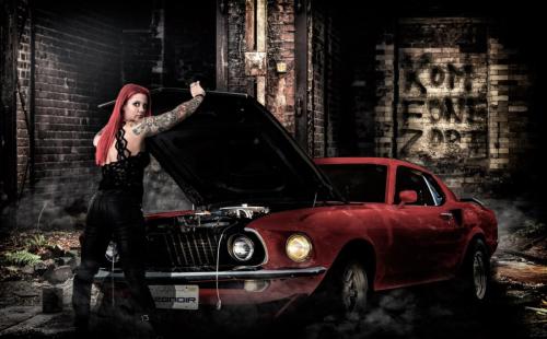 Frau mit rotem Haar vor einem roten Muscle Car