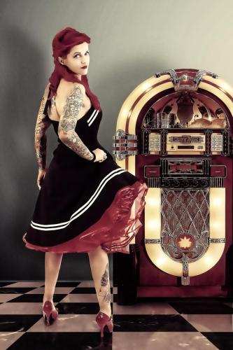 Rockabilly Frau im schwarz rotem Kleid vor einer Jukebox
